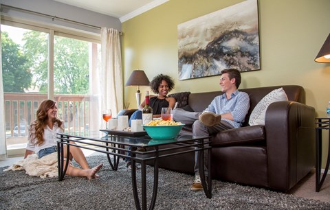 three people sitting on a couch in a living room