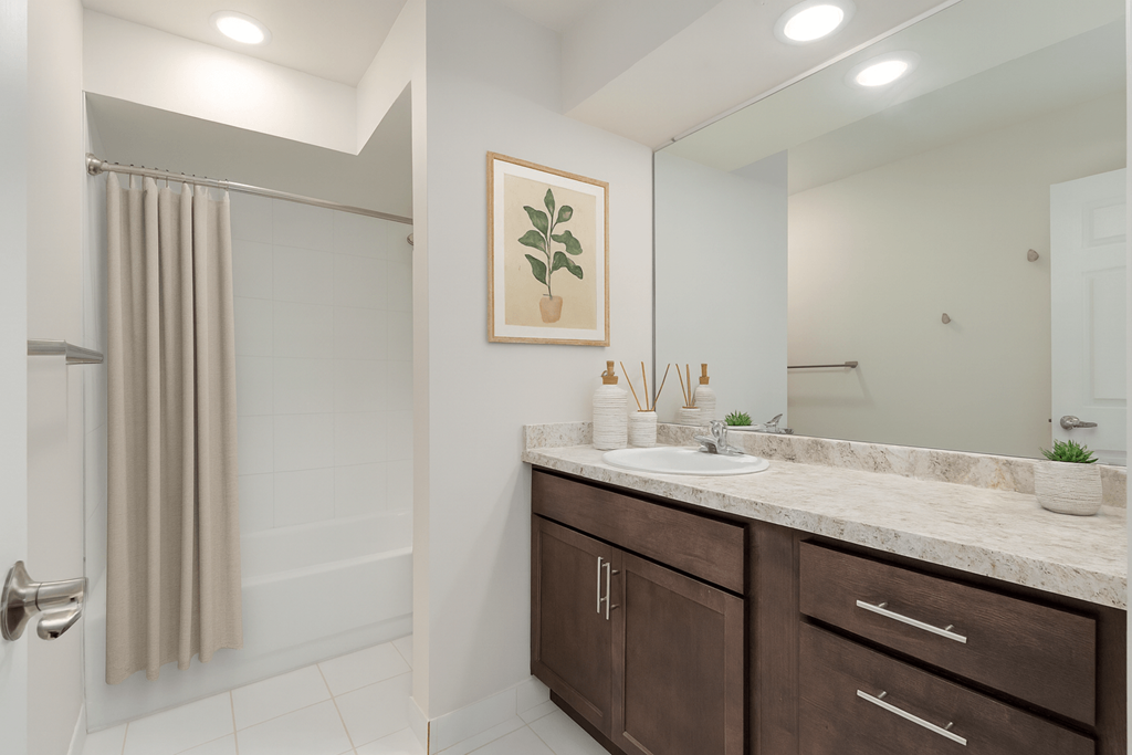 A bathroom with a brown cabinet and a framed picture of a plant on the wall.