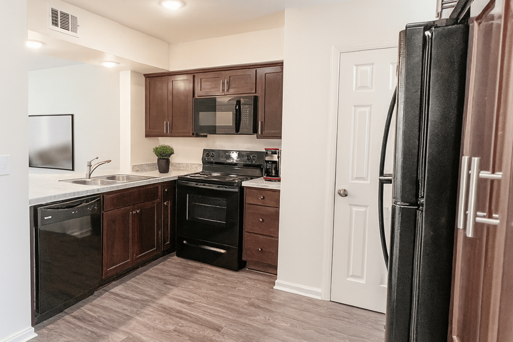 A kitchen with a black refrigerator and brown cabinets.
