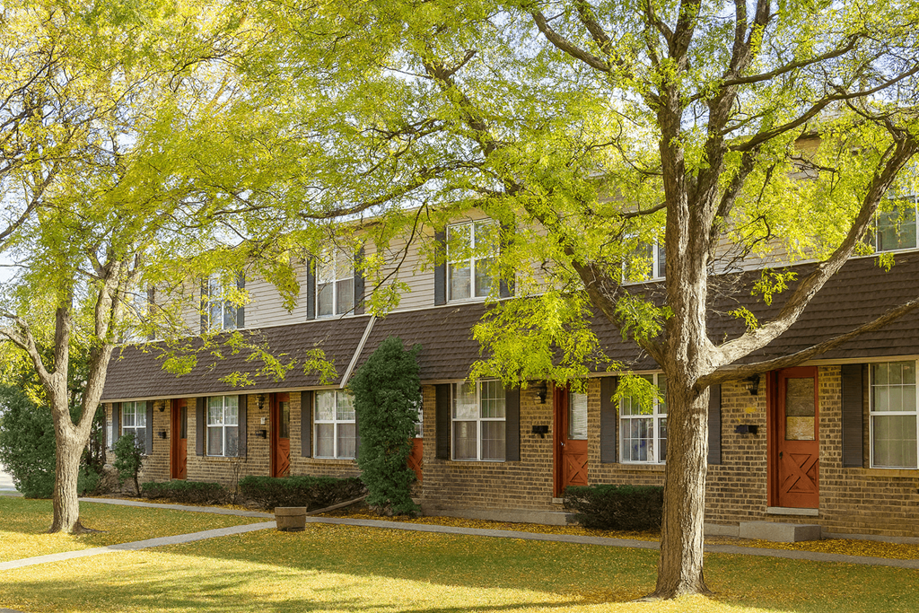 A tree with yellow leaves stands in front of a house.