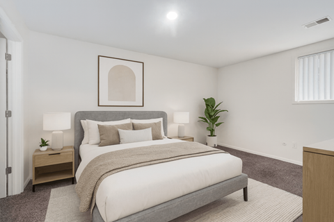 A bedroom with a large bed and a plant on the side table.
