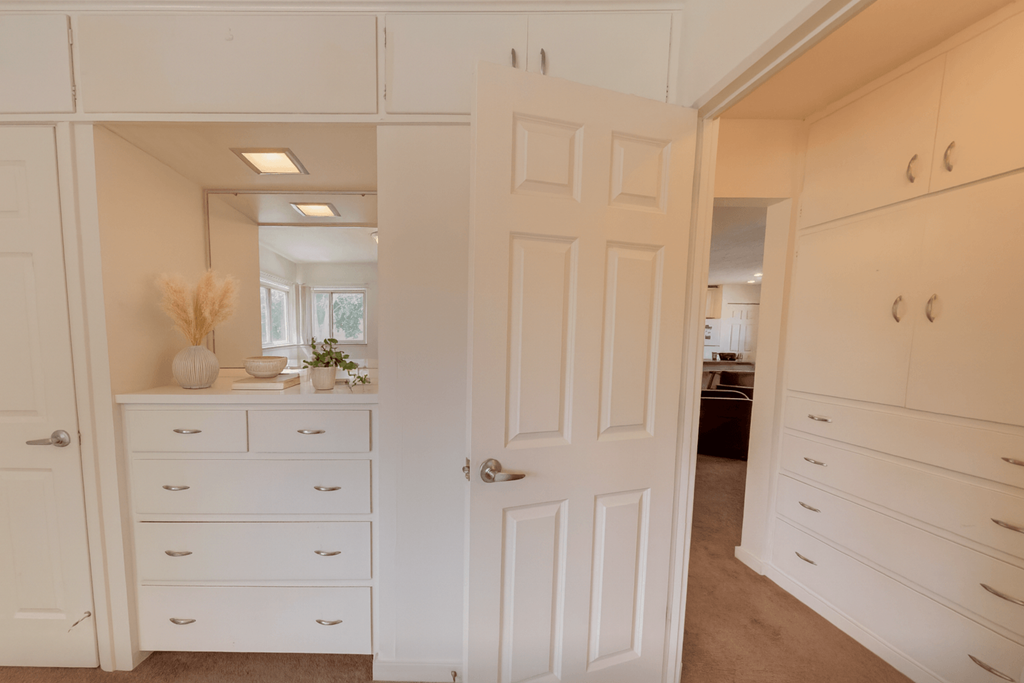 A white room with a door and drawers.