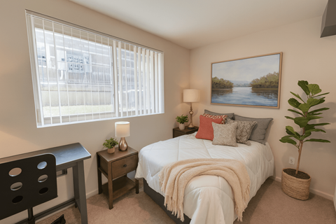 A bedroom with a bed, desk, chair, and a painting on the wall.