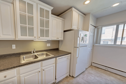 A kitchen with white cabinets and a white refrigerator.
