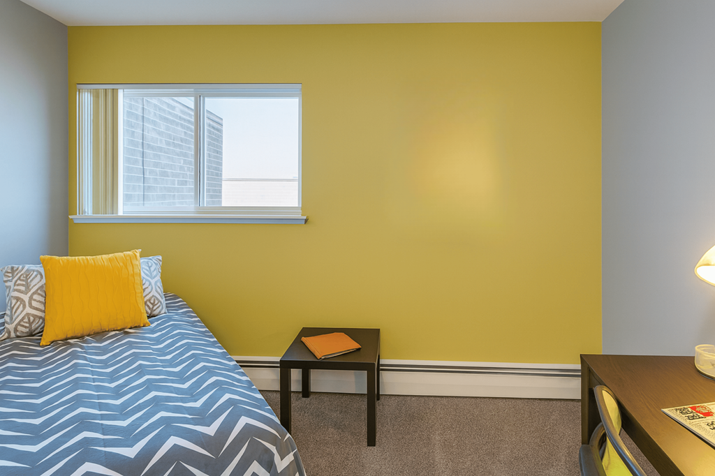 A bedroom with a bed, a small table, and a window.