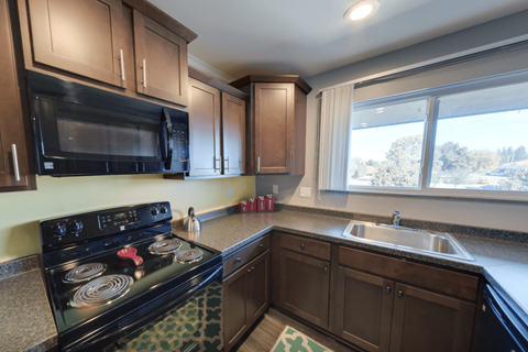 A kitchen with a black stove top oven and wooden cabinets.