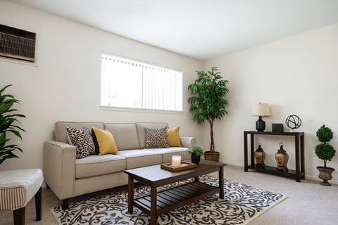 A living room with a beige couch, a coffee table, and a potted plant.