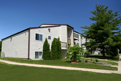 A modern building with a grey facade and a green lawn in front.