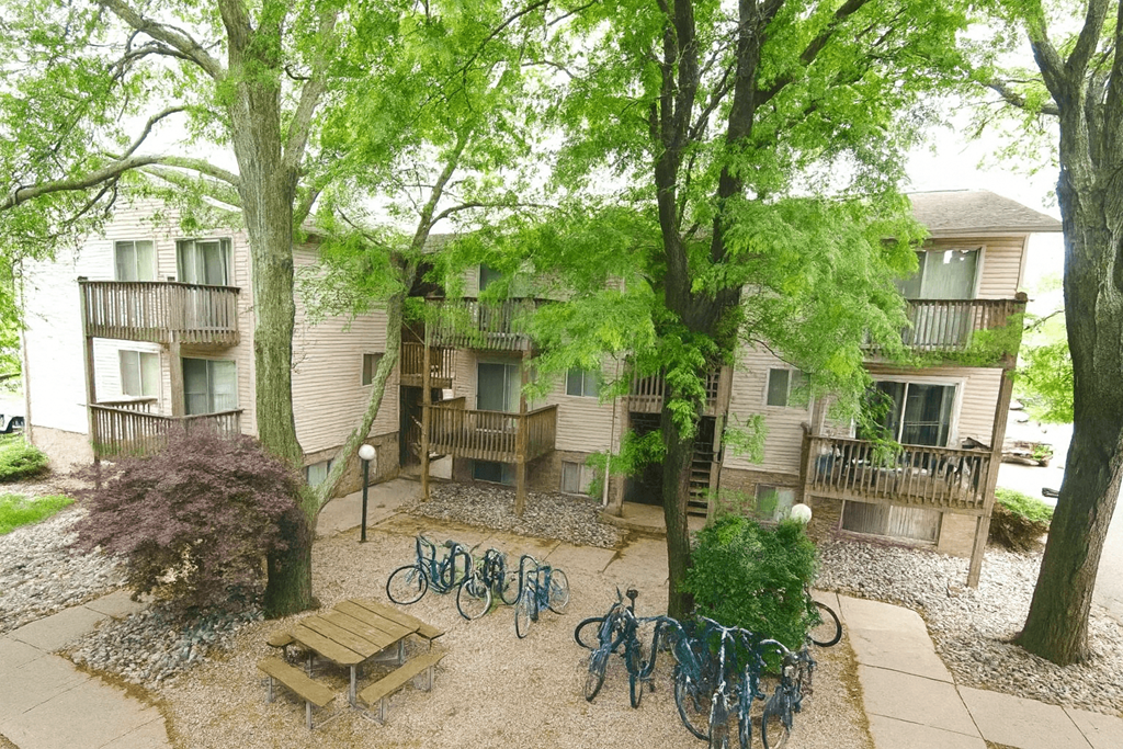 A courtyard with bicycles and a bench surrounded by trees.