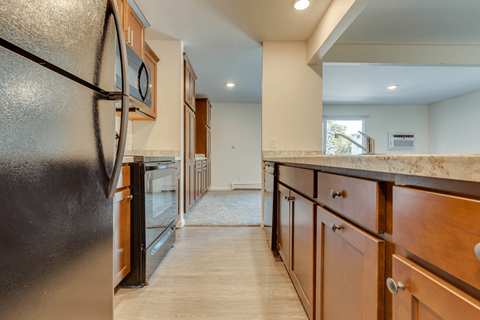 A kitchen with a black refrigerator and wooden cabinets.