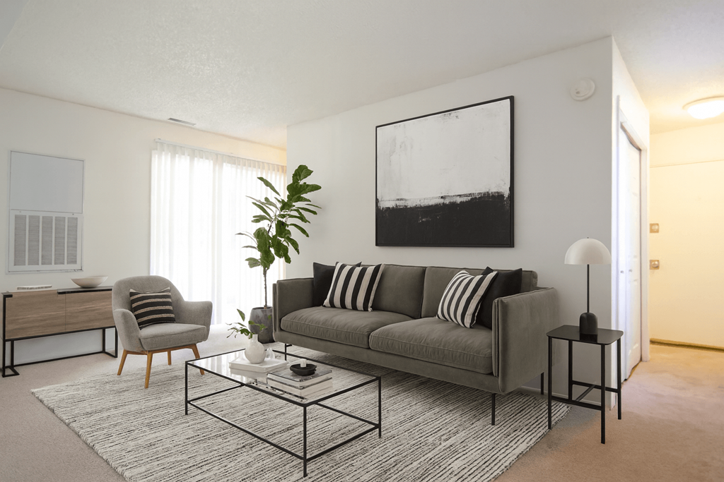 A living room with a grey couch, a coffee table, and a painting on the wall.