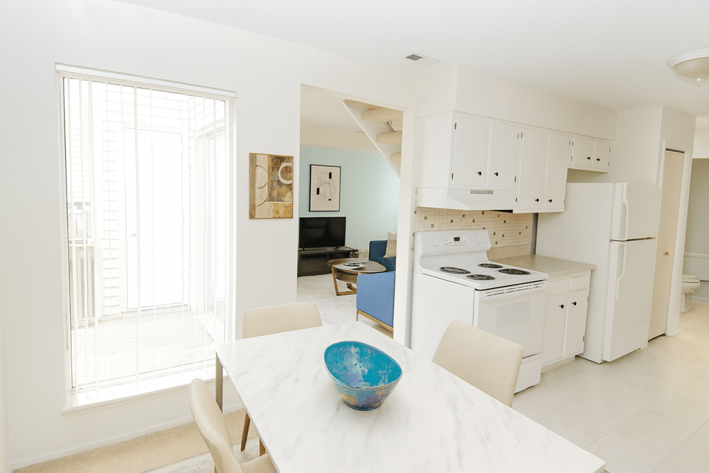A white dining table with a blue bowl on it.