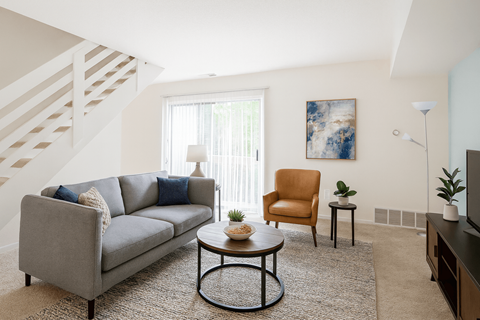 A living room with a grey couch, a brown chair, a coffee table, and a painting on the wall.