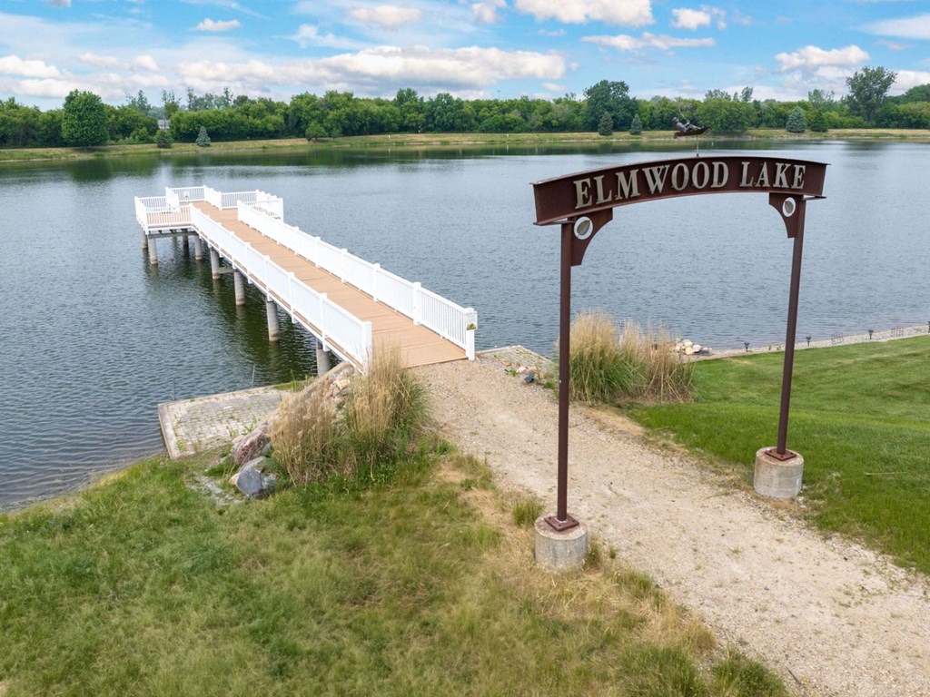a dock on a lake with a wooden sign in the foreground