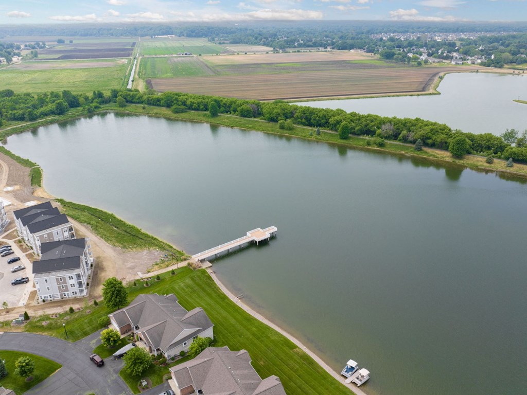 a drone shot of a lake with a bridge in the background