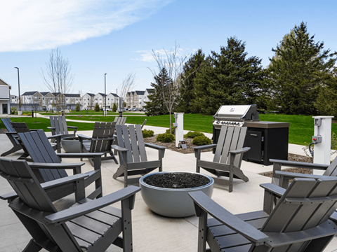 A set of wooden chairs are arranged around a fire pit.