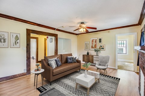 A living room with a brown couch and a ceiling fan.