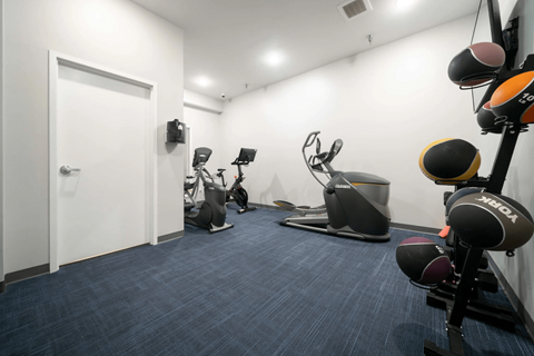 A gym with a variety of equipment including a treadmill, rowing machine, and weights.