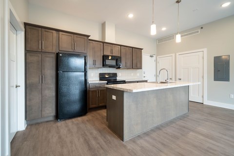 A kitchen with a black refrigerator and wooden cabinets.