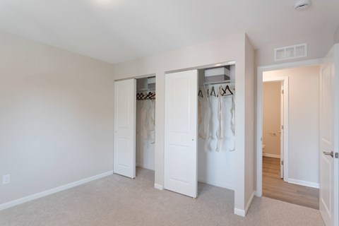 A bedroom with a white door and a white wall.
