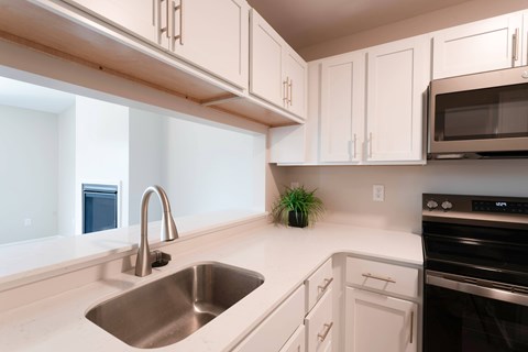 A kitchen with white cabinets and a stainless steel sink.
