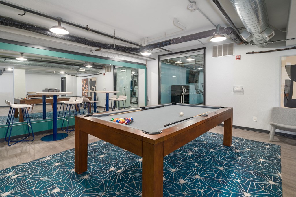 a pool table sits in the middle of a room with a bar in the background