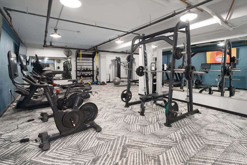 a spacious fitness room with cardio machines and weights
