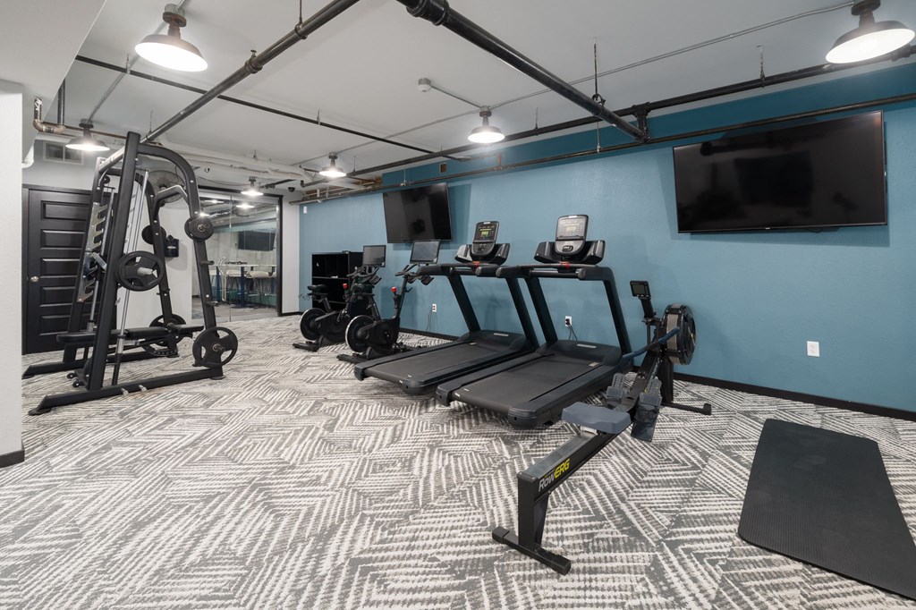 a spacious fitness room with cardio equipment and a flat screen tv