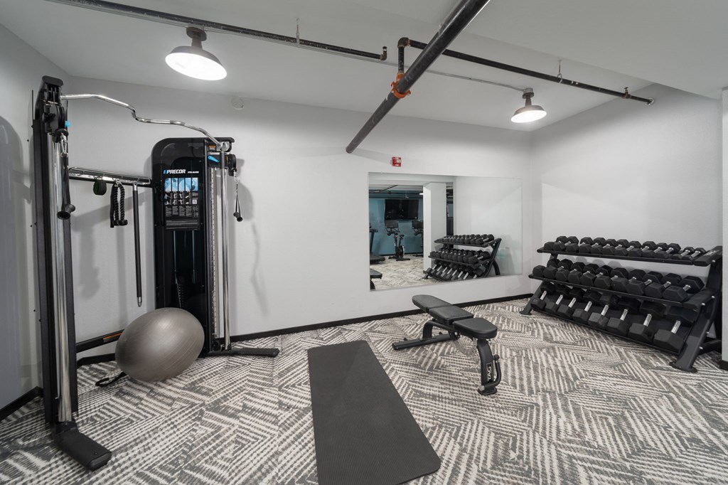 a spacious fitness room with cardio machines and weights