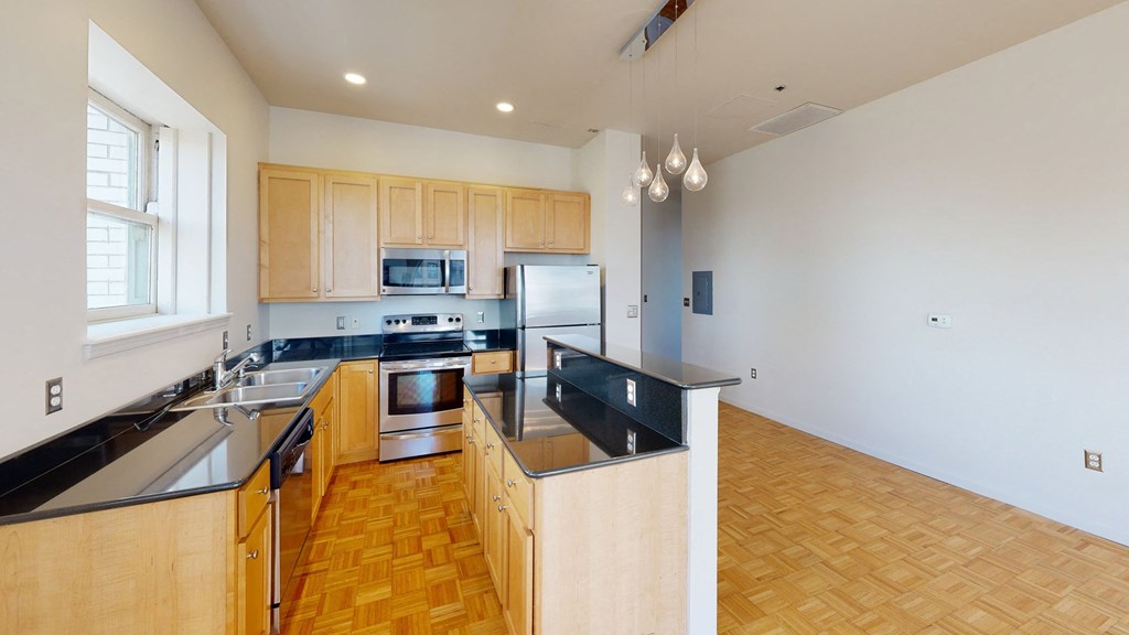 a kitchen with black countertops and wood flooring