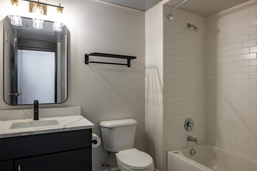 a bathroom with a toilet sink and mirror and a bath tub