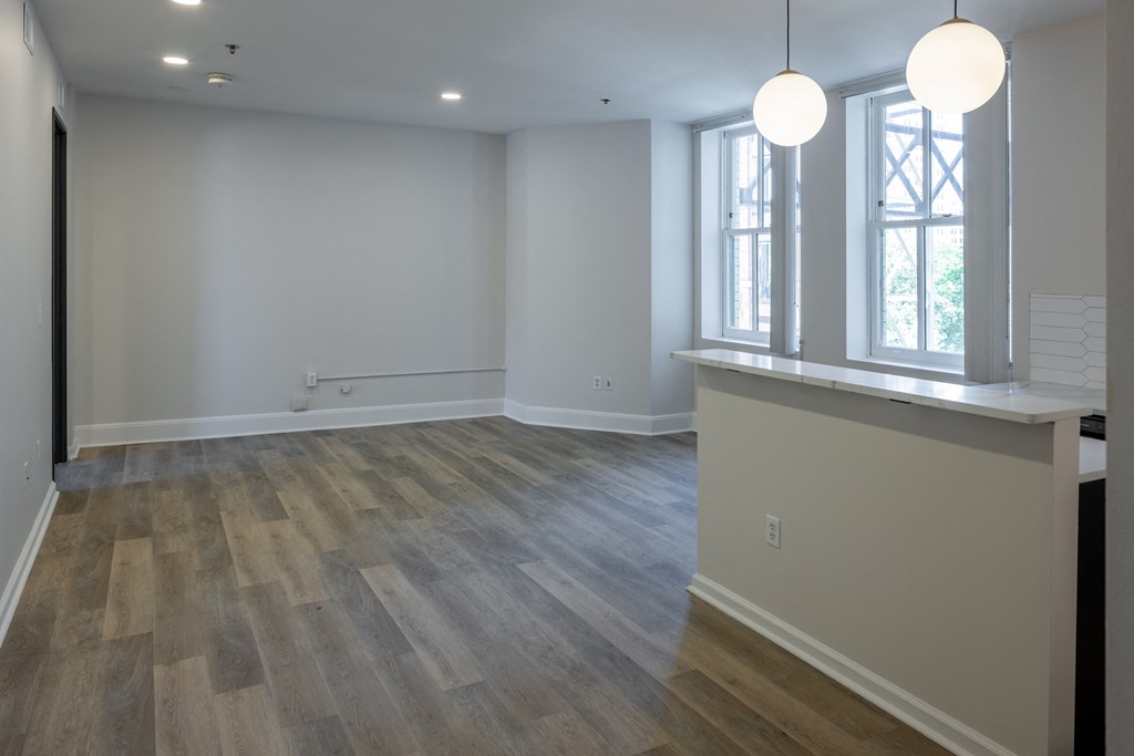 a kitchen and living room with white walls and wood floors