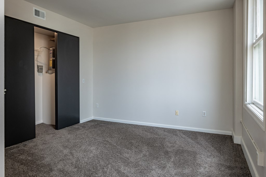an empty living room with carpet and a door to a closet