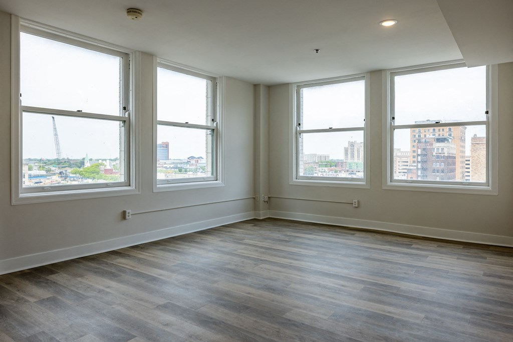 an empty living room with wood floors and four windows