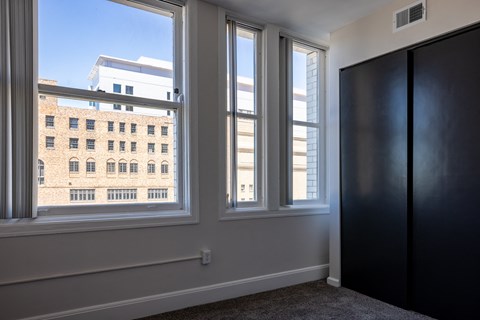 room with three windows and a door and a view of a building