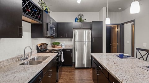A modern kitchen with dark cabinets and a stainless steel refrigerator.