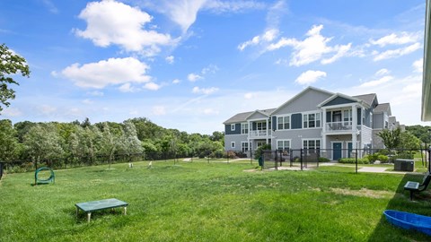 A large grassy field with a playground and a building in the background.