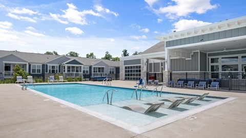 A swimming pool with lounge chairs and a building in the background.