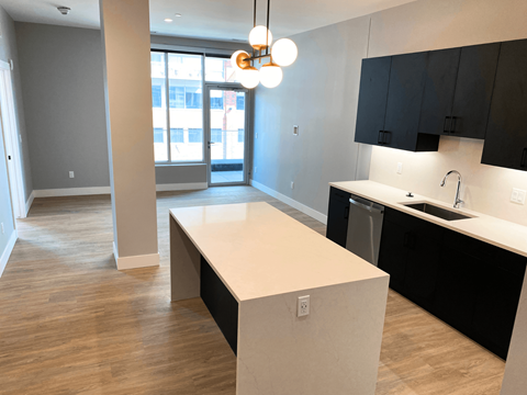 A kitchen with black cabinets and a white island.