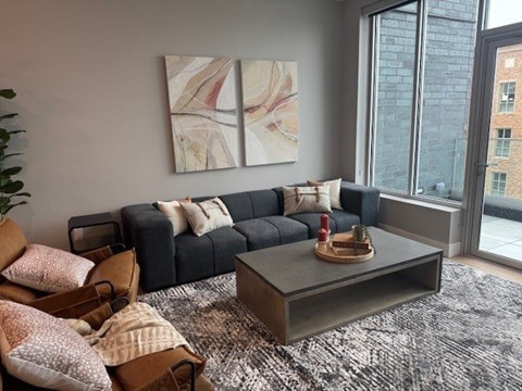 A living room with a grey couch, a coffee table, and a painting on the wall.