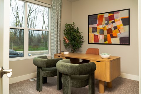 A room with a green chair and a painting on the wall.