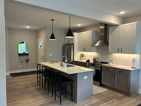 A kitchen with a white counter top and wooden floors.