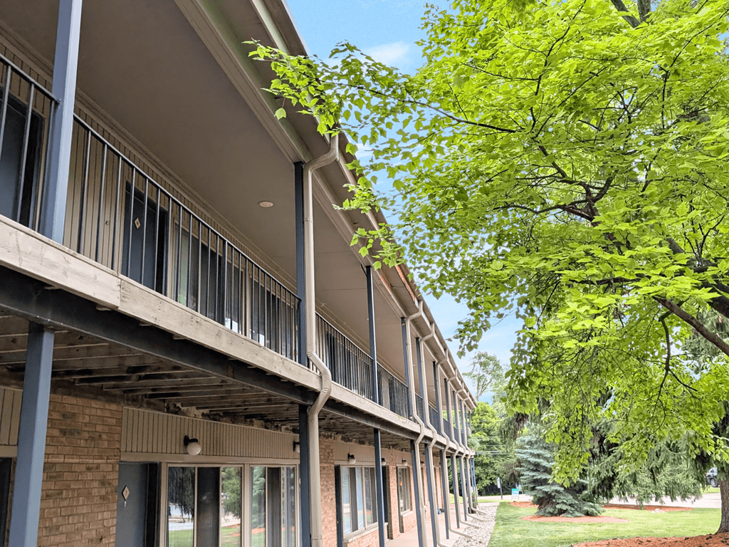 A row of apartment buildings with balconies and trees in the background.