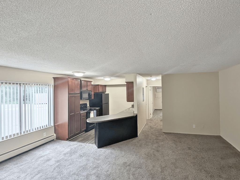 A spacious living room with a black sofa and a television.