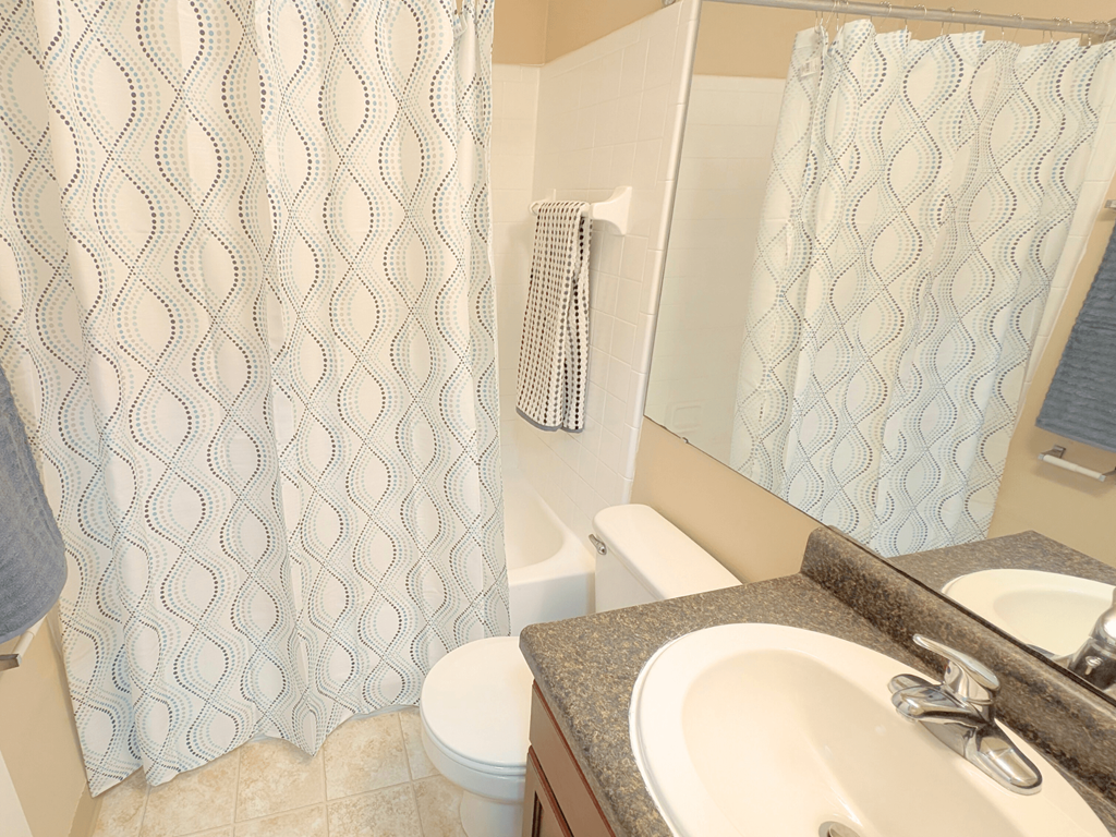 A bathroom with a toilet, sink, and shower curtain.