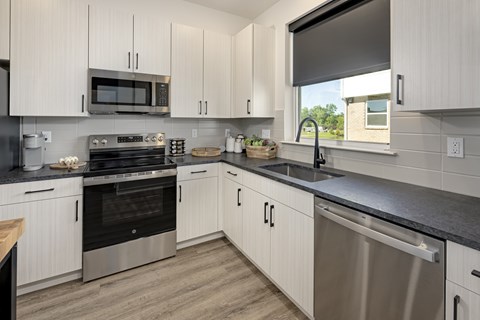 A modern kitchen with white cabinets and stainless steel appliances.