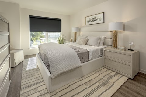 A bedroom with a large bed and a striped rug.
