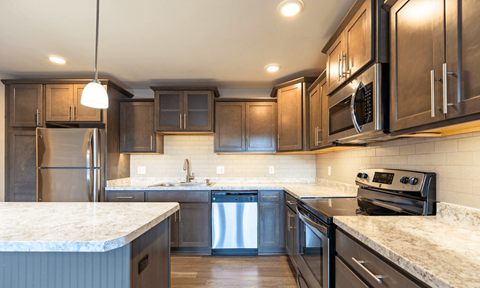 A modern kitchen with dark wood cabinets and stainless steel appliances.