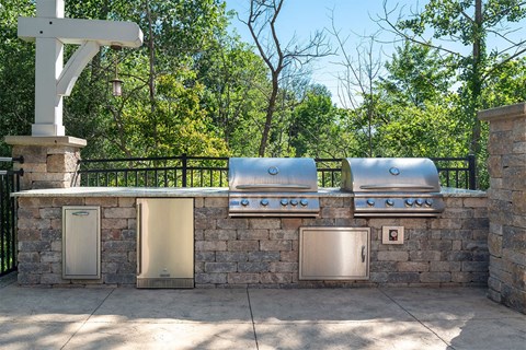 an outdoor kitchen with stainless steel appliances and a stone wall