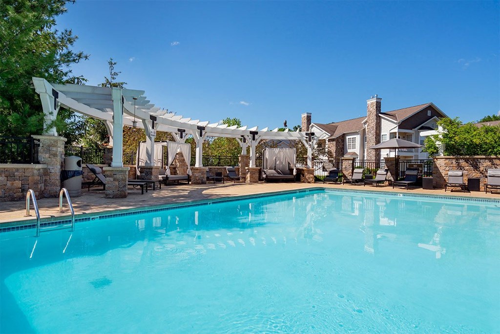 a swimming pool with a pergola over it and a house in the background